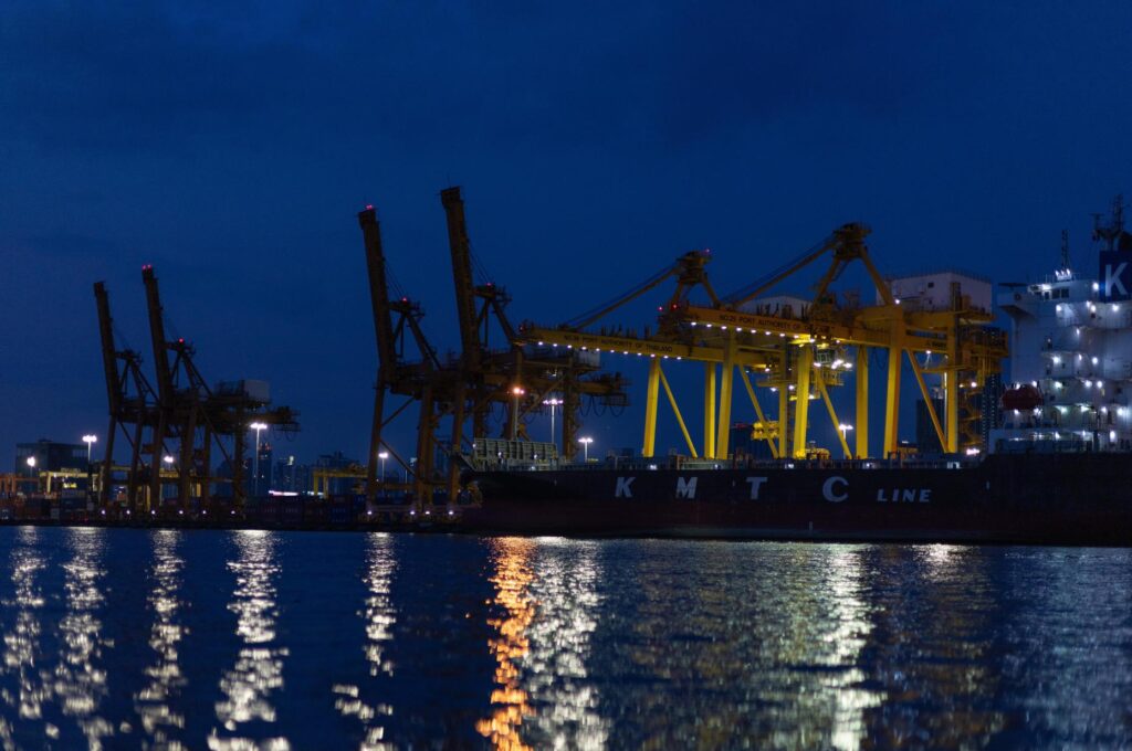 Night lights from Khlong Toei Pier shimmer on the Chao Phraya River in Bangkok.