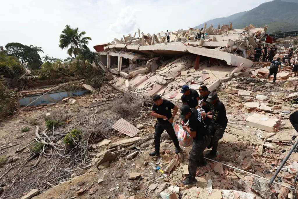 Police carry a body recovered from the rubble of a...