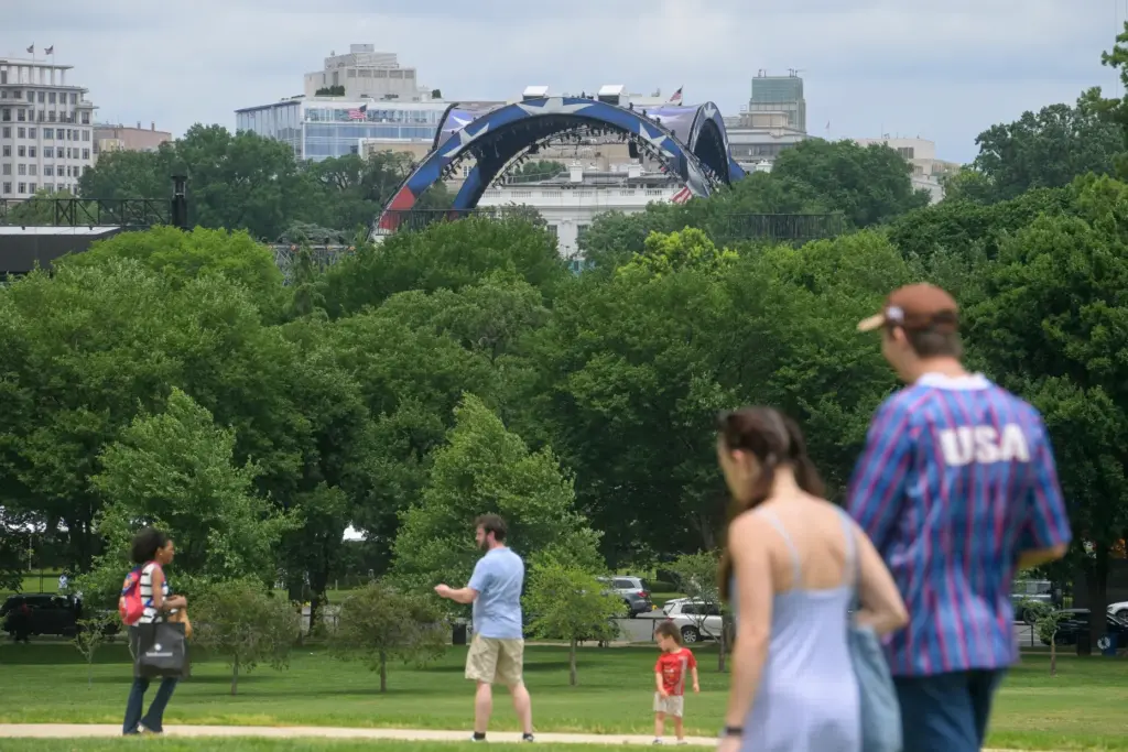 People walk near the Washington Monument as workers continue building...