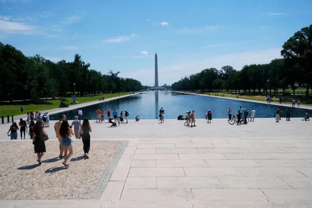 Visitors on the National Mall walk around the Reflecting Pool.