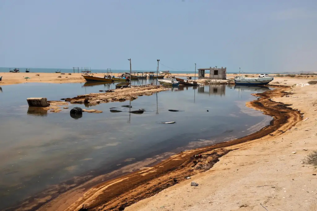 Oil residue lines the shore near fishing boats on Qeshm...