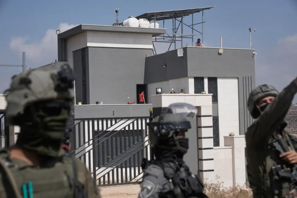 Israeli army soldiers block the road leading to the houses...