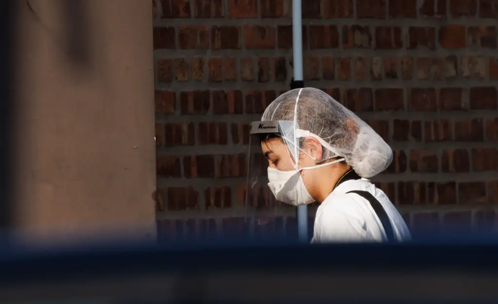 A worker with a mask and face shield walks at...