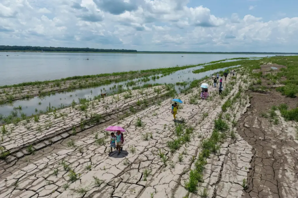People walk through a part of the Amazon River that shows signs of drought.