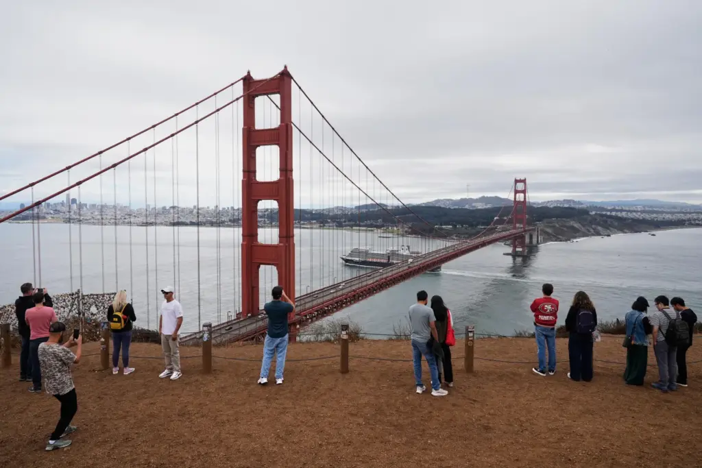 FILE – People look at and photograph the Golden Gate...