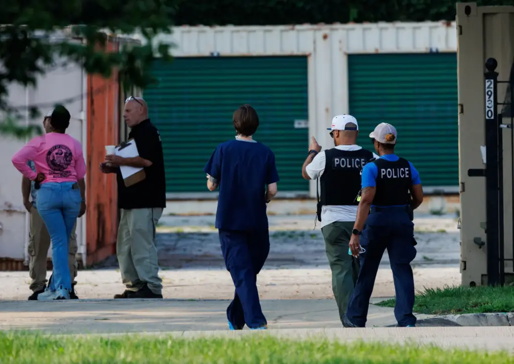 Chicago police and other officials work the scene where many...