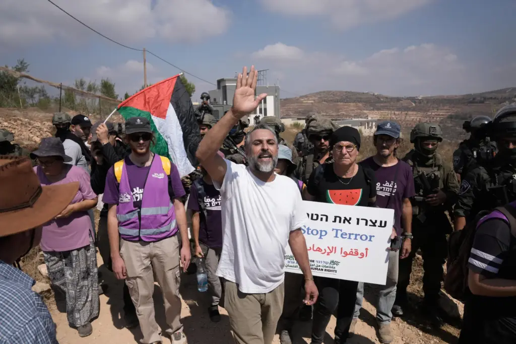 Activists march with food and water supplies toward the houses...