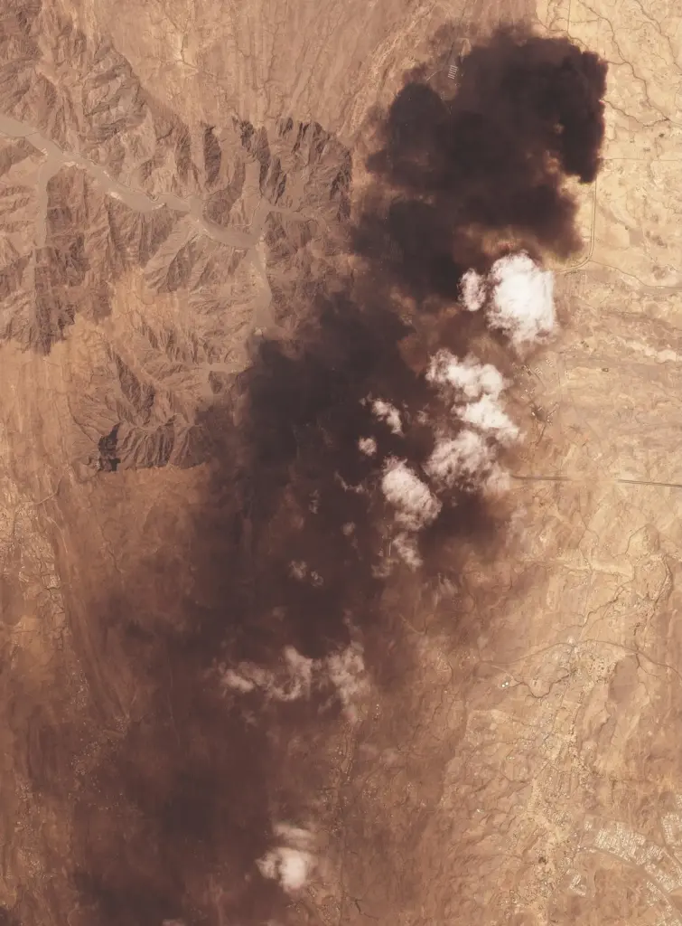 A satellite image shows plume of black smoke rising from a Saudi Aramco oil refinery.
