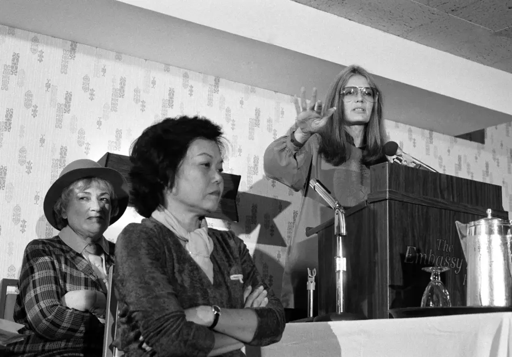 Bella Abzug and Patsy Mink of Women USA sit next to Gloria Steinem as she speaks.