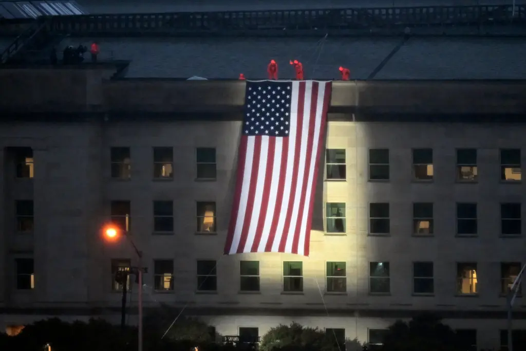 Service members unfurl a flag on the 25th anniversary of 9/11 at the Pentagon.