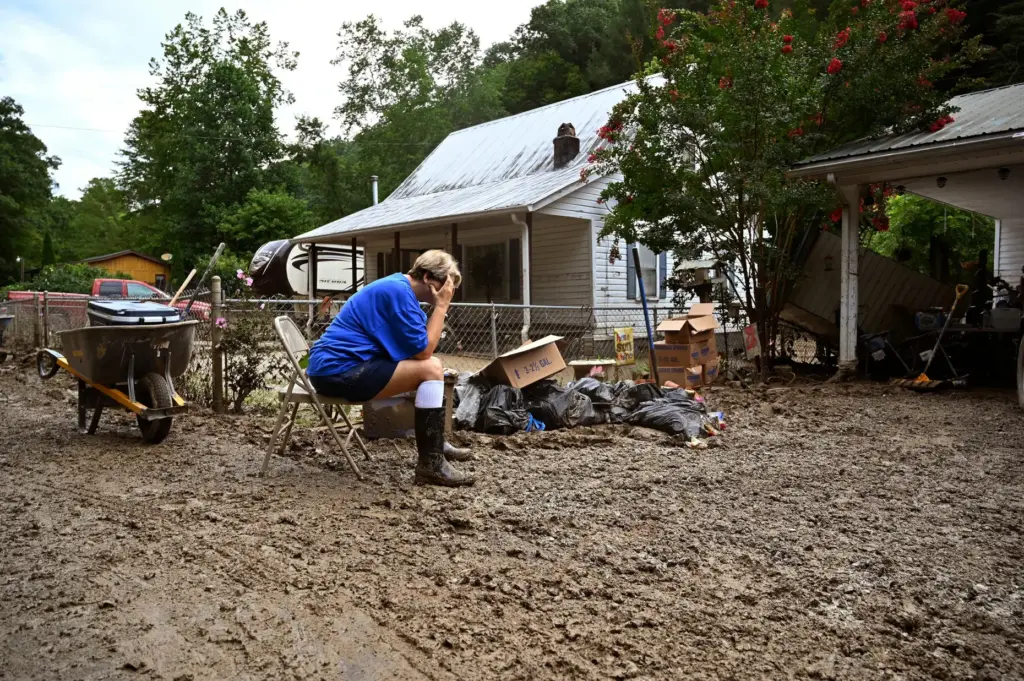 Teresa Reynolds sits exhausted as members of her community clean debris from flooding.