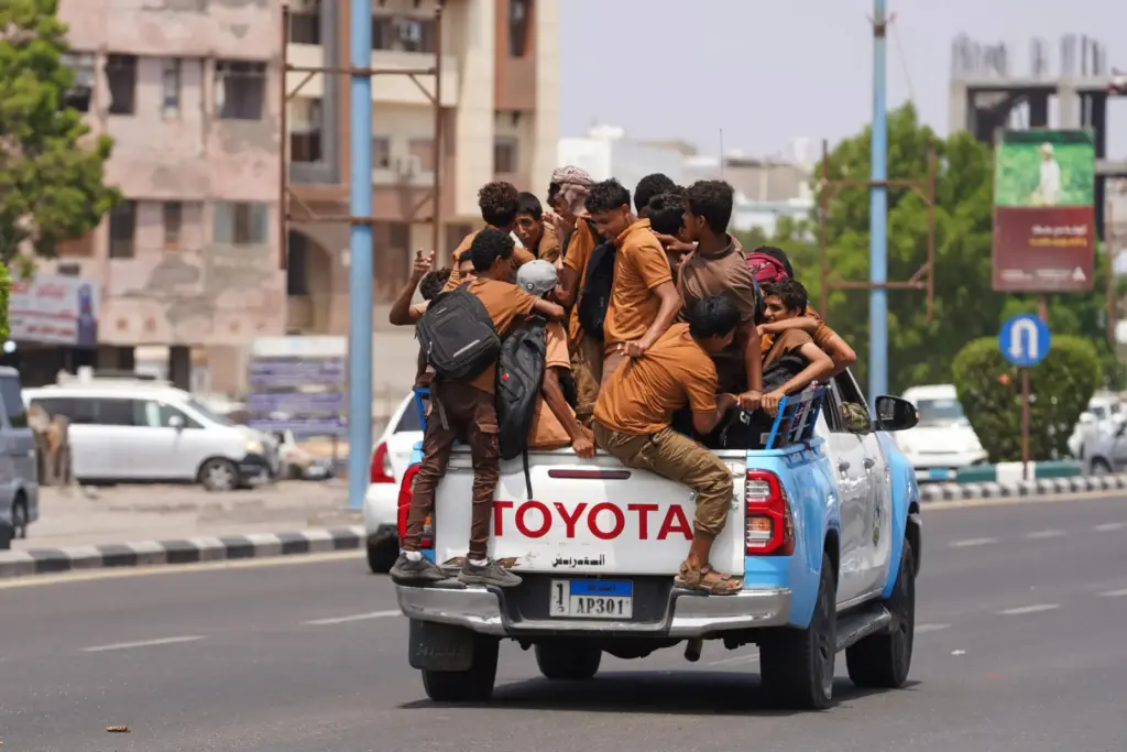 Schoolboys ride in the back of a police pickup truck after classes in Aden, Yemen.