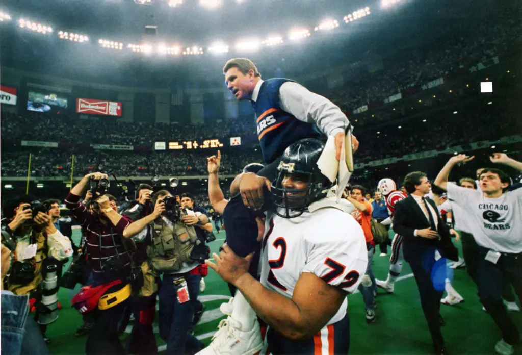 Coach Mike Ditka is carried off the field by William...